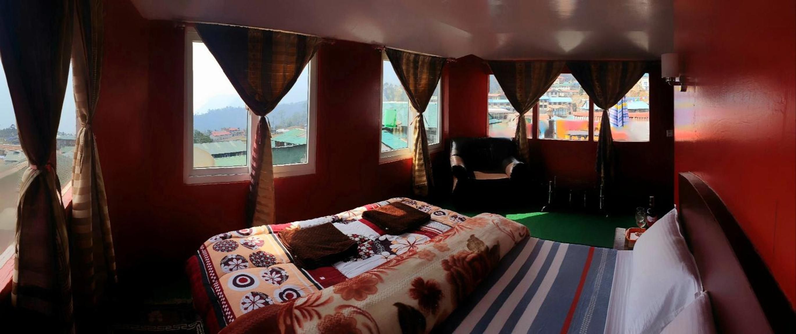 Una habitación con una cama, una silla y vistas a un paisaje urbano a través de ventanas.