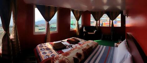 Una habitación con una cama, una silla y vistas a un paisaje urbano a través de ventanas.