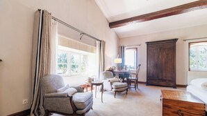 Una habitación con un gran armario de madera, una cama, una mesa de comedor con sillas y una ventana con cortinas.