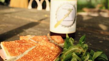 A sandwich on a plate with a bottle of beer in the background.