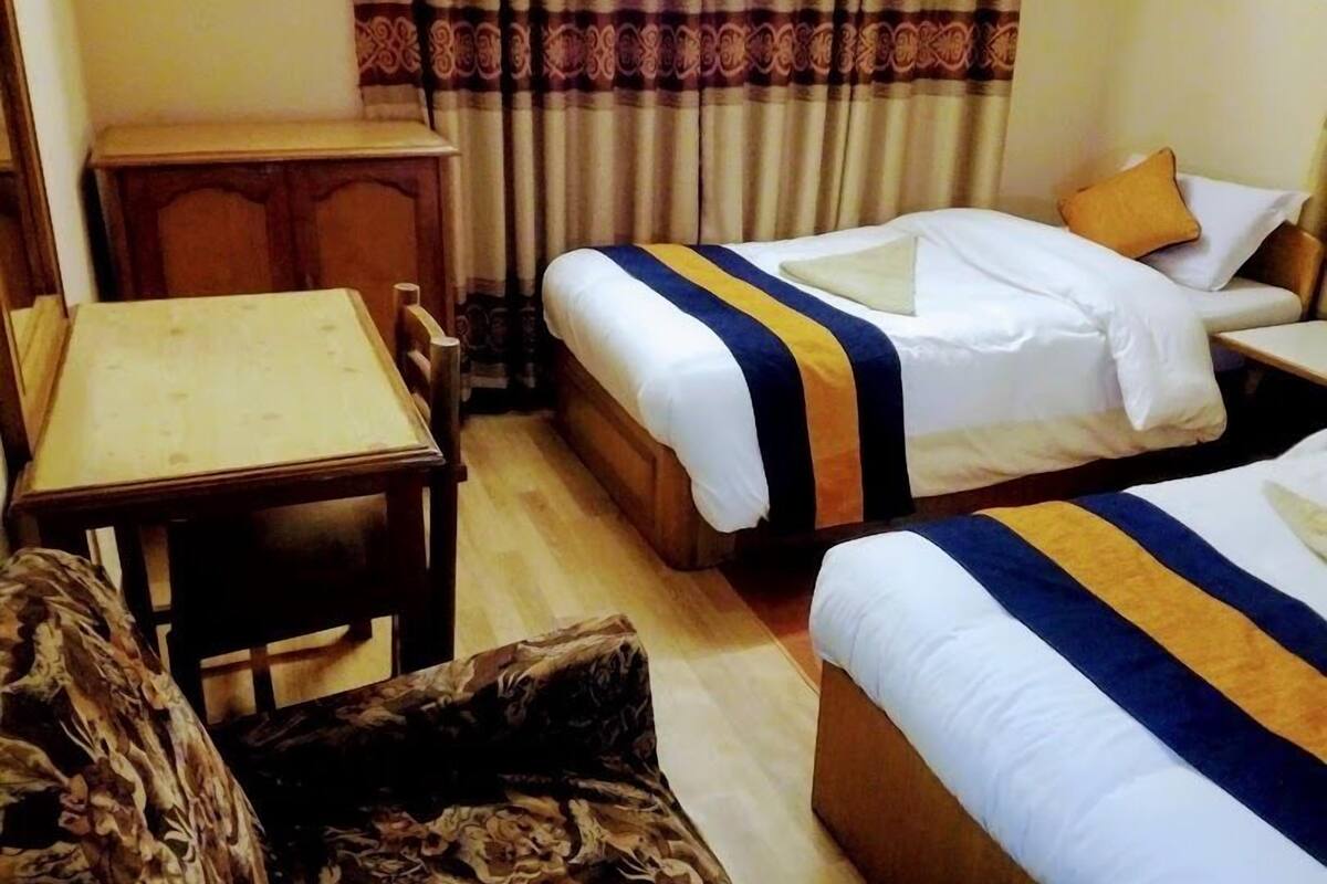 Una habitación de hotel con dos camas, un escritorio de madera y una mesita pequeña.