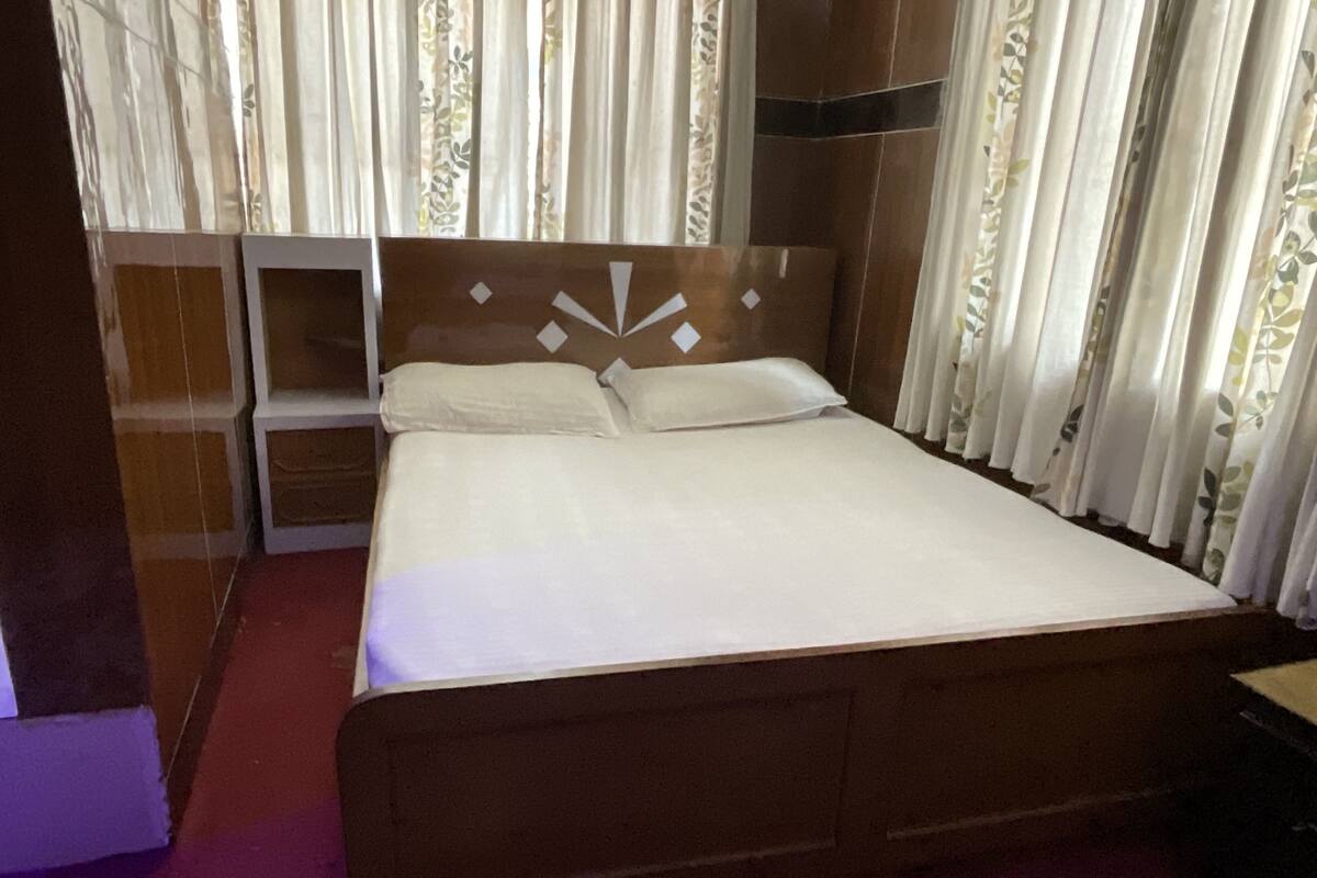 A standard hotel room with a wooden bed, a nightstand, and a built-in shelf.