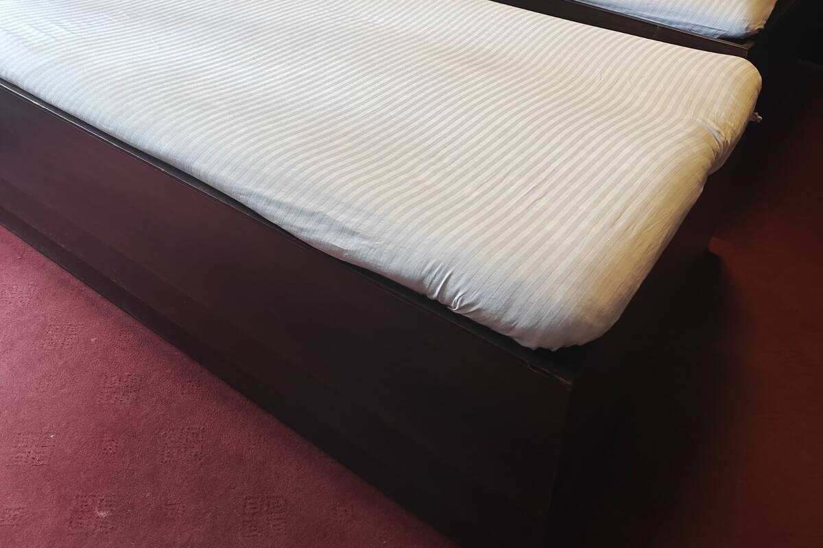 Two single beds with headboards, a wooden headboard bed, and a red carpet.
