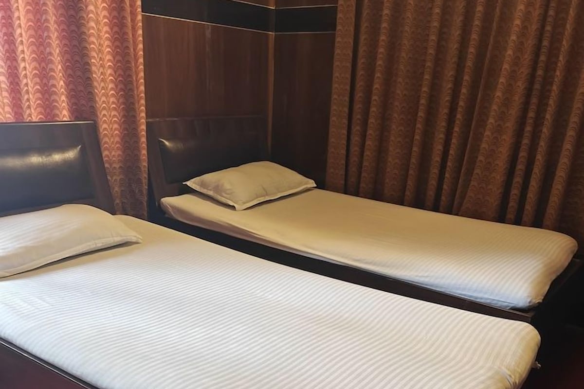 A room with two beds, each with a headboard and a pillow.