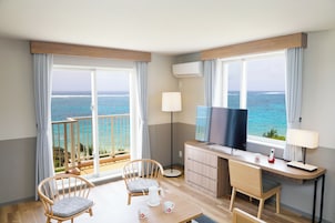 A hotel room with a balcony, a TV, a desk, and two chairs.