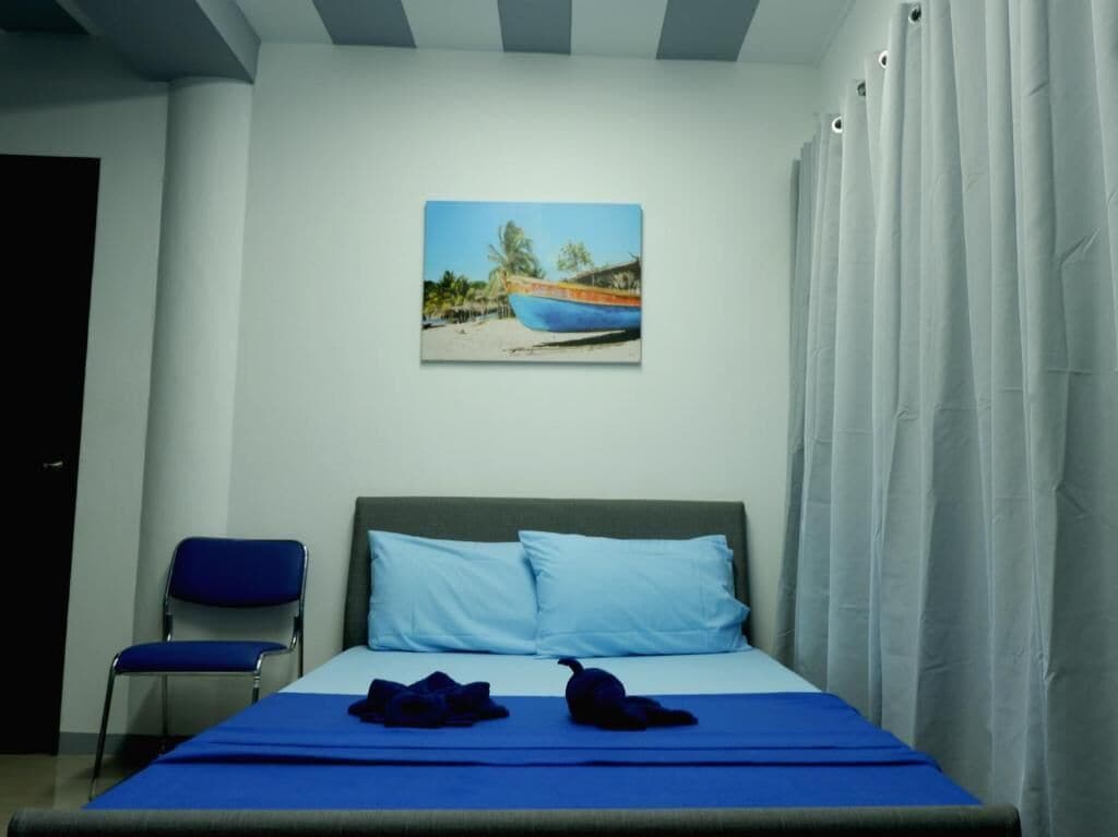 A bedroom with a bed, a chair, and a painting of a boat on the wall.