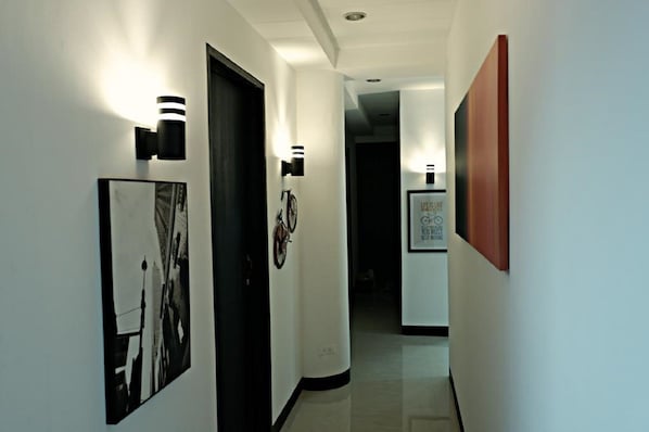 A hallway with framed artwork on the walls, a bicycle, and a door.