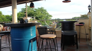 Un patio al aire libre con un barril azul, una mesa de madera redonda y dos sillas.
