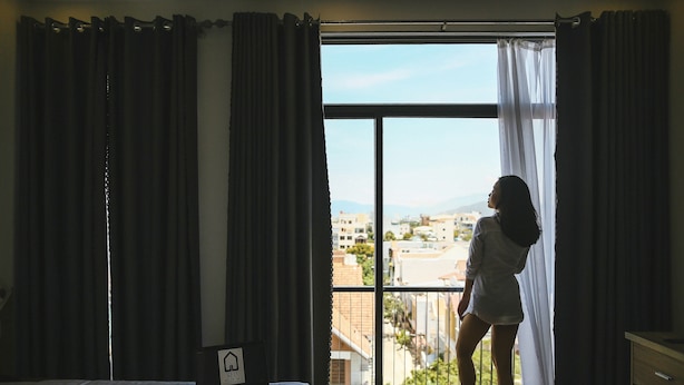 A bedroom with a large window, a bed, a bedside table with a fruit plate, and a sign indicating a bed and breakfast. - Red Hotel Da Nang (Da Nang)