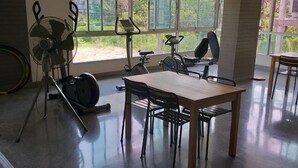 A gym with exercise equipment, a table, and chairs. - J 168 Living (Bangkok)