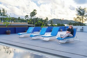A poolside area with lounge chairs and potted plants. - Kokotel Phuket Patong (Patong)