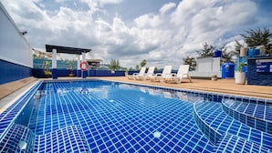 Piscina amb rajoles blaves, gandules i una zona coberta.