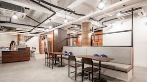 Un interior modern amb una taquilla de fusta, una taula de dinar llarga amb caires i una banca amb coixins.