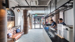 Un vestíbul d'hotel modern amb taulell de recepció, zona de seients i grans finestres.