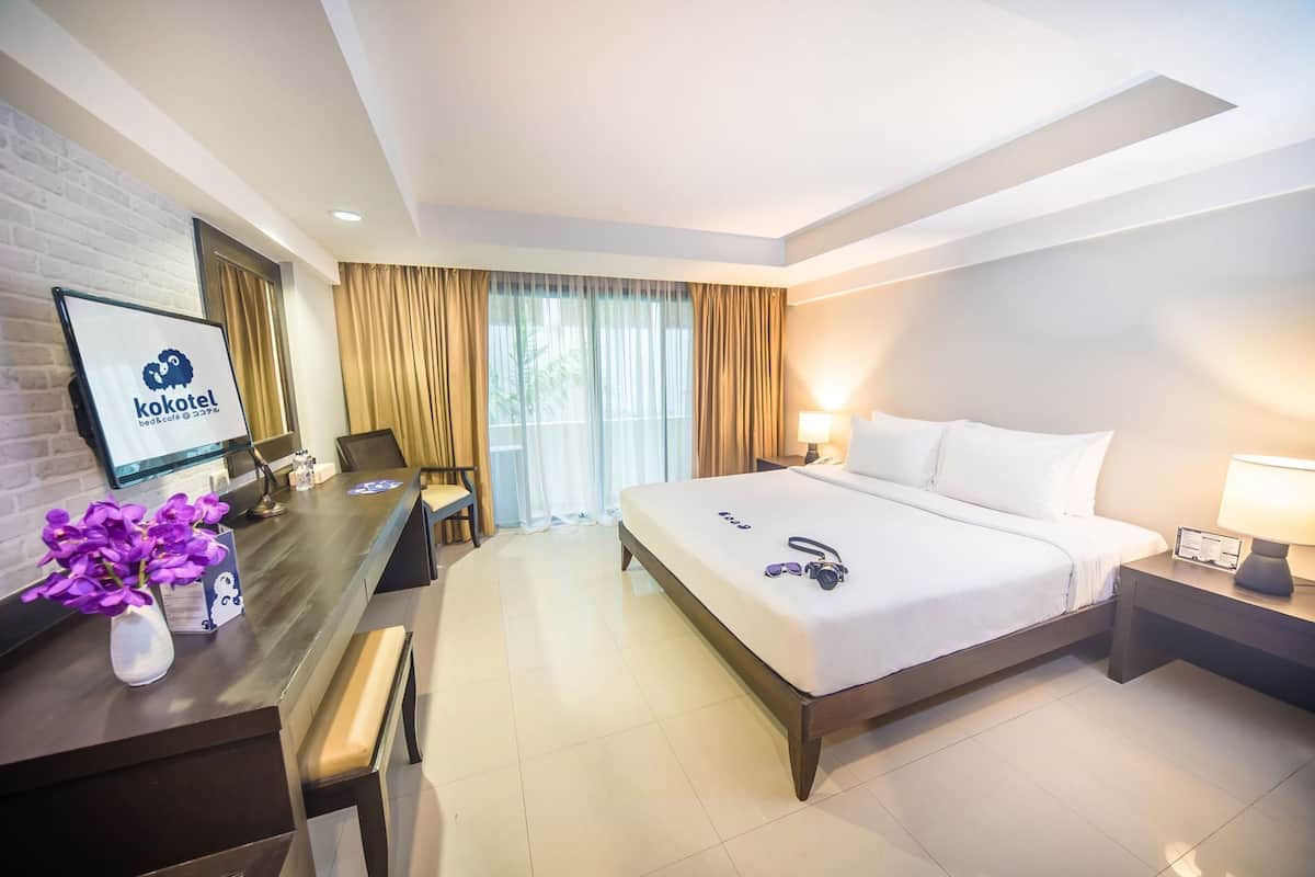 A hotel room with a bed, desk, chair, and a sign for 'kokotel bed & cafe'.