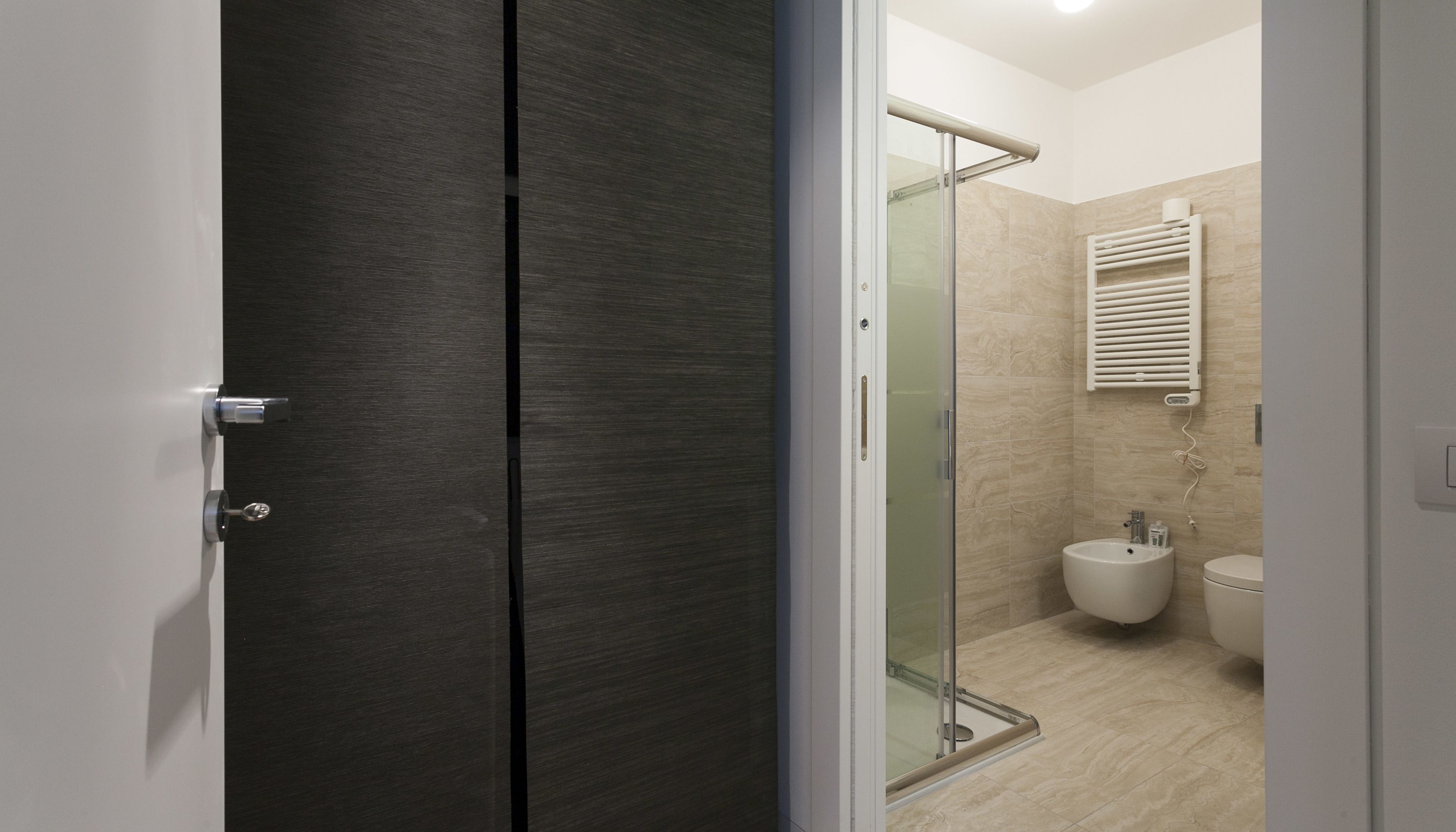 A modern bathroom with a glass shower enclosure, a toilet, and a bidet.