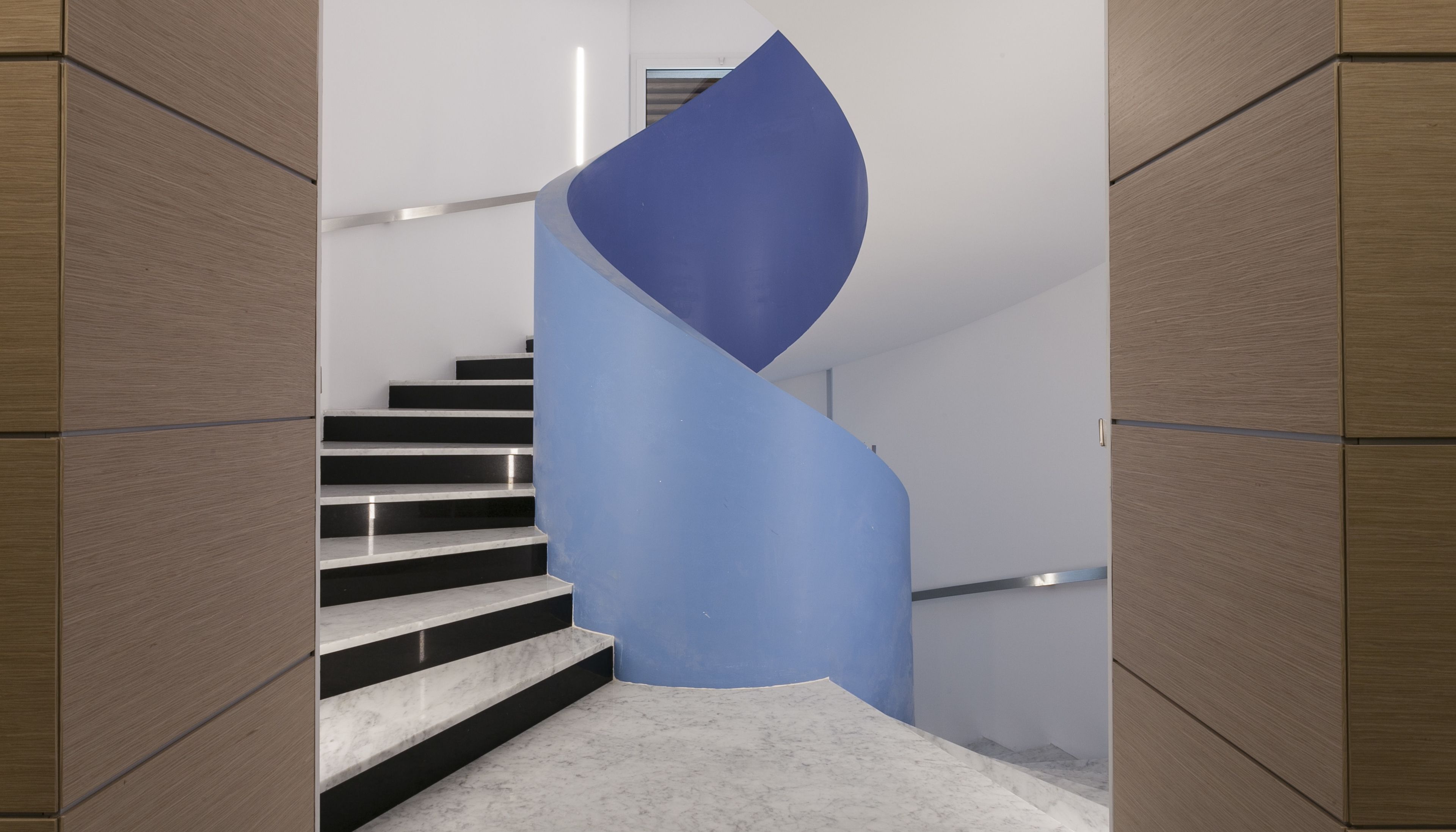 Un escalier moderne avec un mur d’accent bleu et des panneaux de bois sur les côtés.