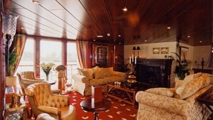 A room with a fireplace, leather armchairs, a wooden floor, and large windows. - Crossgates Hotelship Nizzaufer - Frankfurt (Frankfurt)
