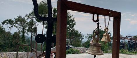 A metal structure with a bell hanging from it, set against a cloudy sky.