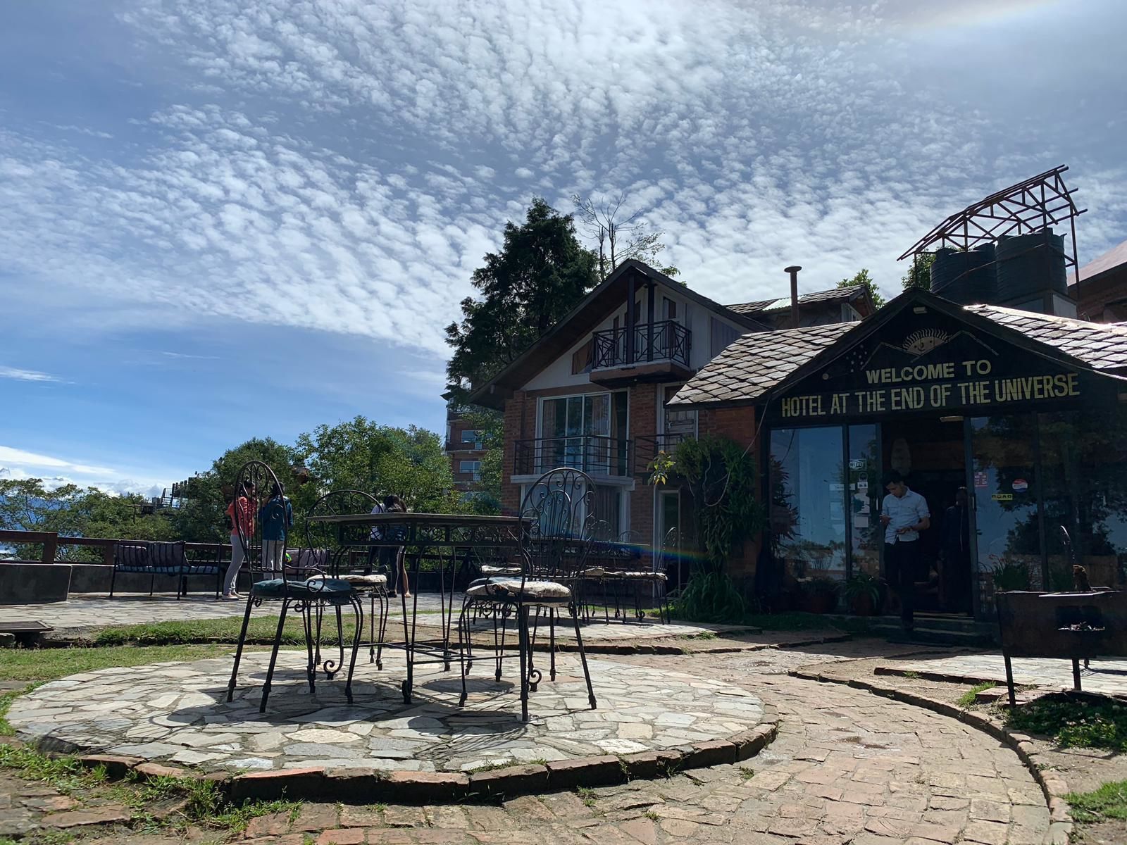 A hotel named "Hotel at the End of the Universe" with a stone patio and outdoor seating.