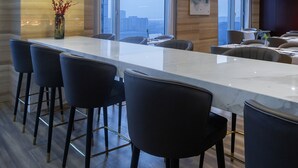 Une cuisine moderne dotée d’un grand îlot central, de tabourets de bar, de luminaires suspendus et offrant une vue sur la ville.