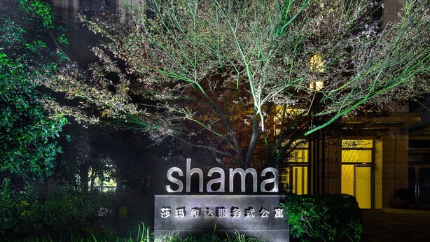 Une pancarte portant le mot « shama » et quelques caractères chinois, le tout entouré de verdure.