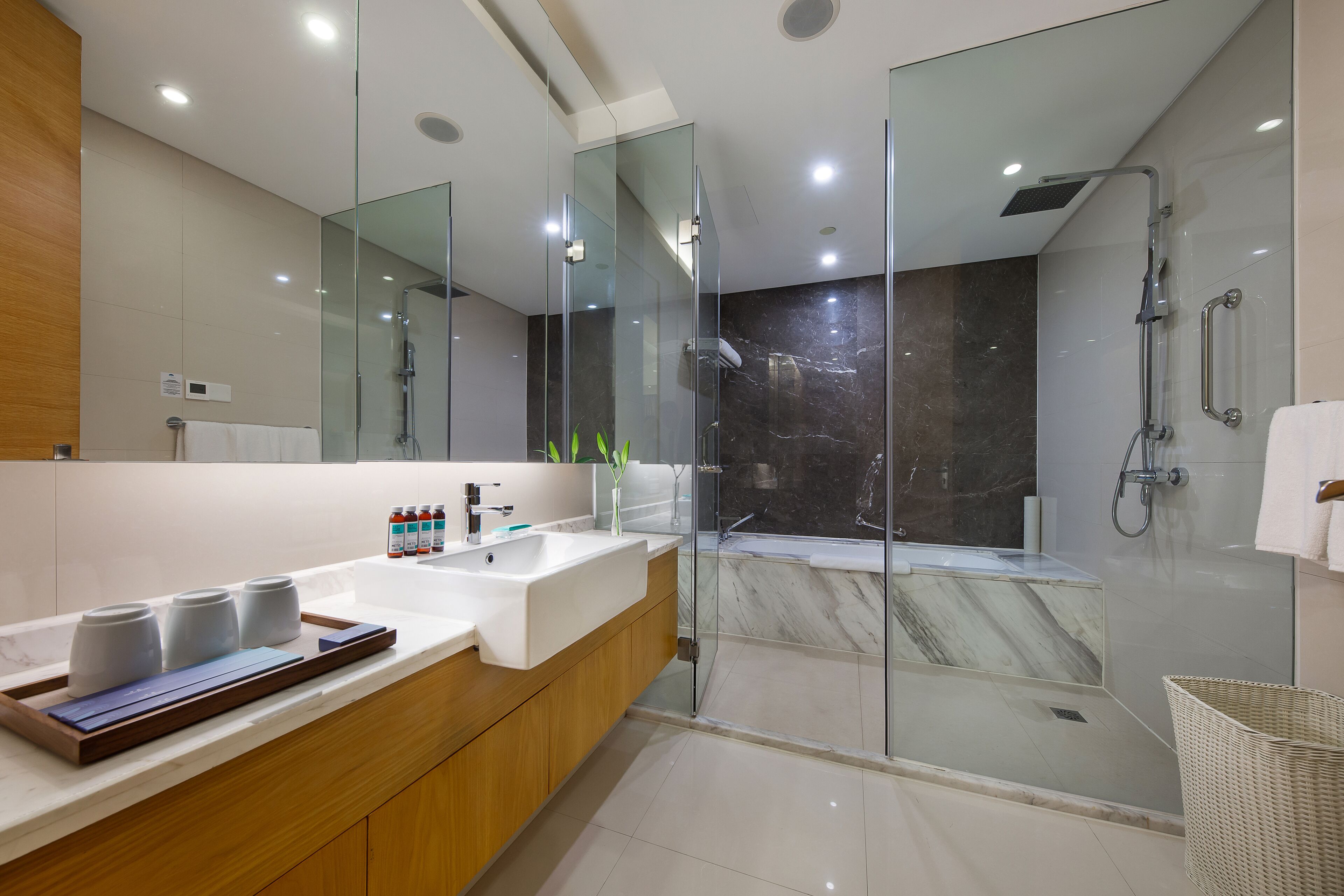 A modern bathroom with a glass-enclosed shower, a marble bathtub, and a vanity with a sink and storage.