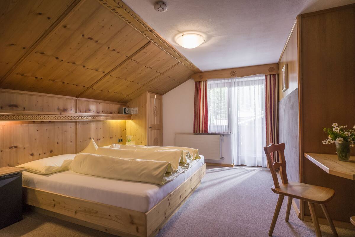Una habitación de madera con una cama, un escritorio y una silla.