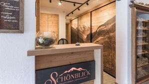 A reception desk with a wooden finish and a glass bowl of decorative items. The wall behind features a large framed picture of a mountainous landscape.