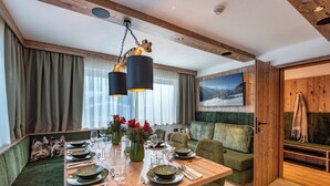 A dining area with a wooden table set for four, surrounded by green upholstered seating.