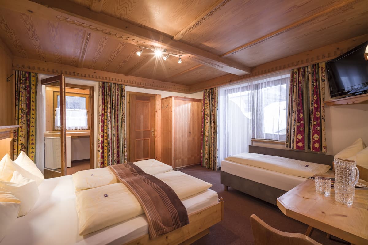 Una habitación con dos camas, un escritorio de madera, una televisión y una ventana con cortinas.