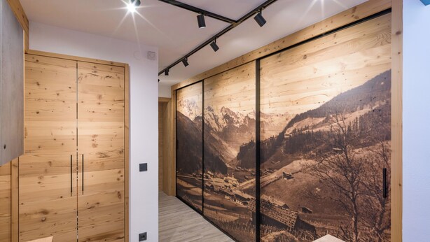 A modern room with wooden panel walls, a desk with a computer, and a large framed picture of a mountainous landscape.