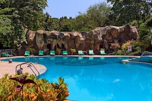 Una piscina al aire libre, sombrillas, sillones reclinables de piscina
