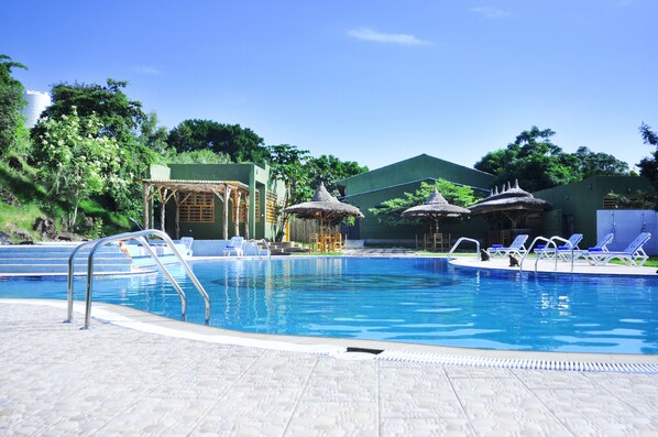 Una piscina al aire libre, sombrillas, sillones reclinables de piscina