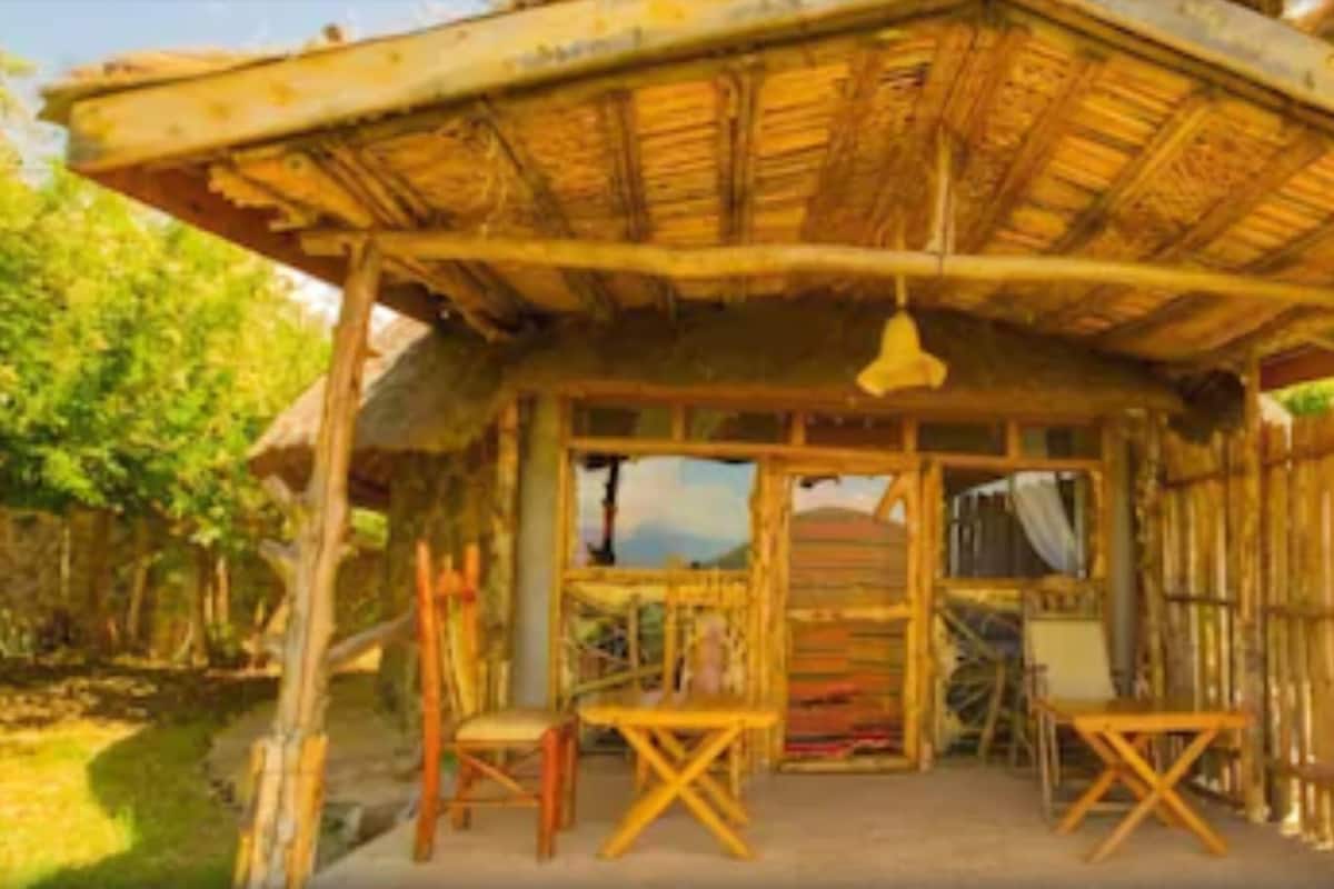 A rustic wooden structure with a thatched roof, a wooden bench, and a table in the center.