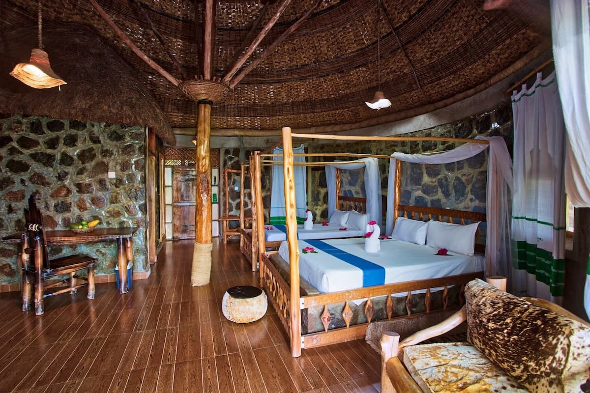 A traditional room with a four-poster bed, stone walls, and a thatched roof.
