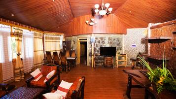 Un salón con suelo de madera, chimenea, zona de estar y televisor.