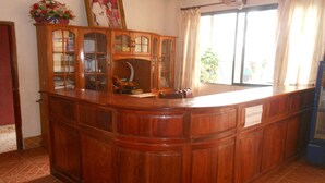 Una zona de bar con madera, que incluye un mueble con puertas de vidrio, una pequeña estatua y un arreglo floral.