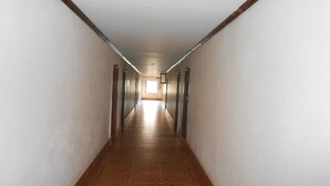 Un pasillo largo y estrecho con piso de baldosas y detalles de madera en las paredes.
