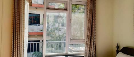 Un dormitorio con cama, ventana y cortinas.