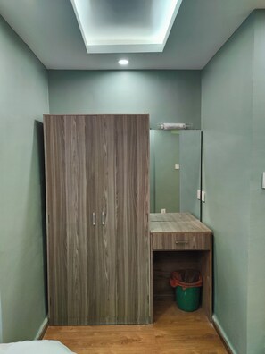 A room with a wardrobe, a mirror, a small desk, and a trash bin. - Family Peace House (Kathmandu)