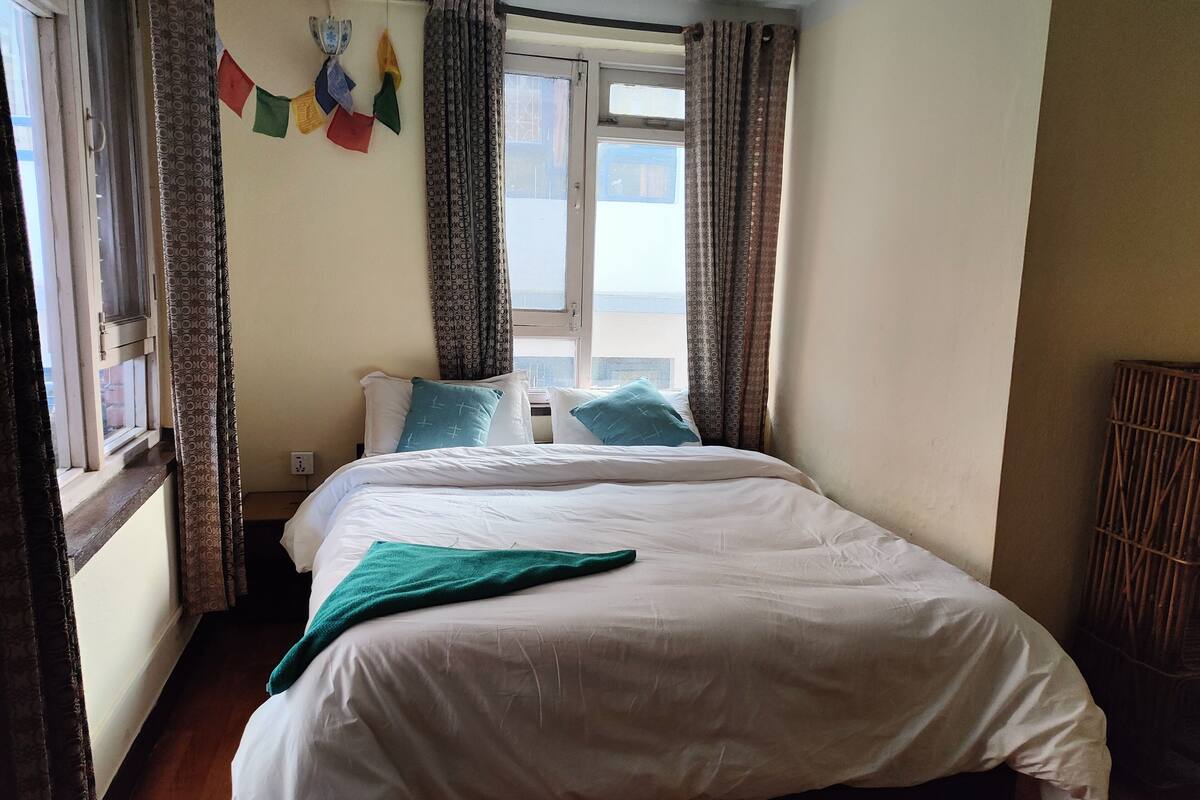 A bedroom with a bed, curtains, and a window.