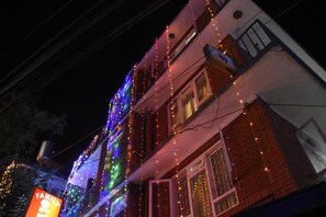 A building with colorful string lights and a sign that reads "FAMILY OF P." - Family Peace House (Kathmandu)