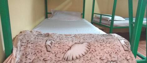 Un lit superposé avec une couverture à motifs et un oreiller uni.