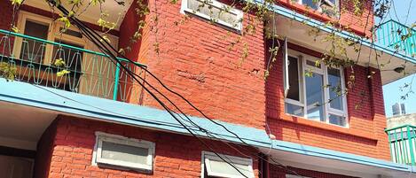 Un edificio de ladrillo rojo con techo azul, un balcón y un letrero que indica una casa de huéspedes y restaurante.