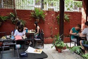 An outdoor cafe with brick walls, potted plants, and metal tables and chairs. - Family Peace House (Kathmandu)