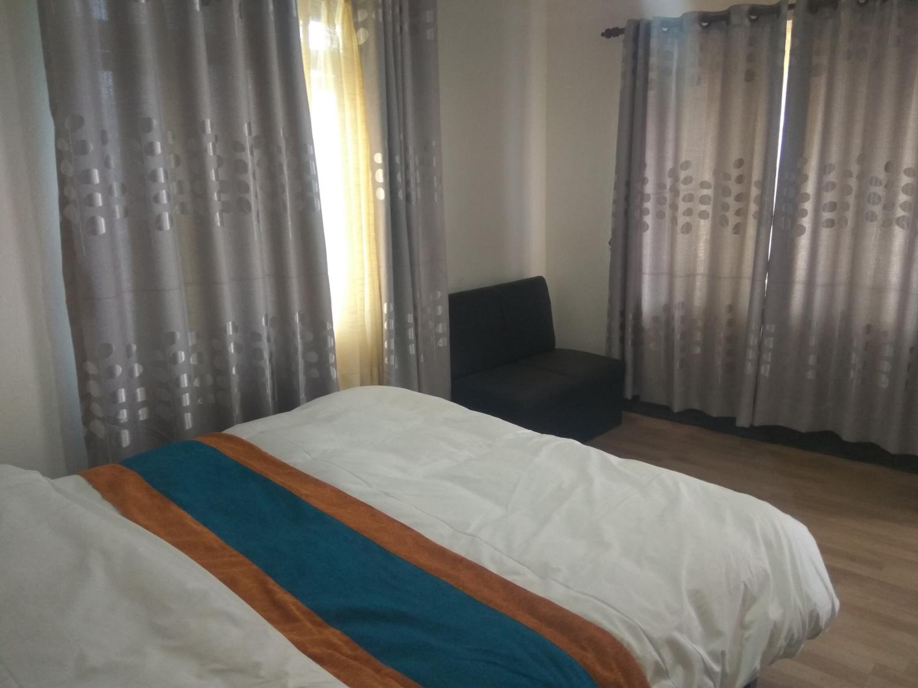 A hotel room with a bed, a chair, and curtains.