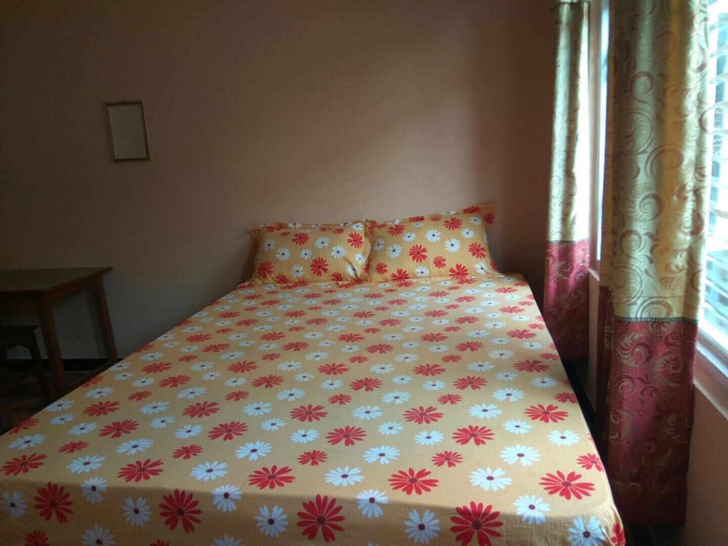 Un lit avec une couvre-lit à motifs floraux, une table de chevet et des rideaux.