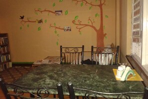 A dining area with a green marble table, four chairs, and a wall mural of a tree with leaves and a bird. - Family Peace House (Kathmandu)