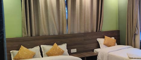 A hotel room with two beds, a wooden headboard, and a large window with curtains.